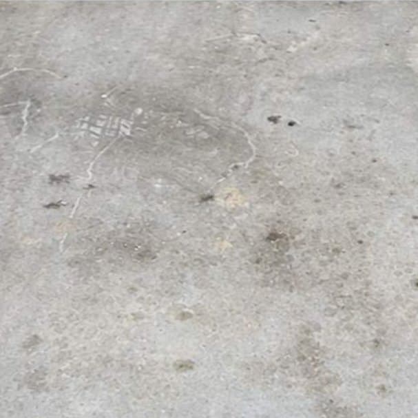 Oil stain on a parking garage floor before and after degreasing by Ascension Exterior Services