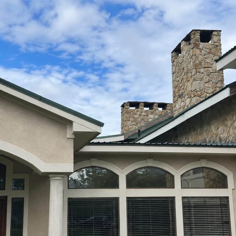 Stone chimney, gable and roofline before and after a soft wash by Ascension Exteriors