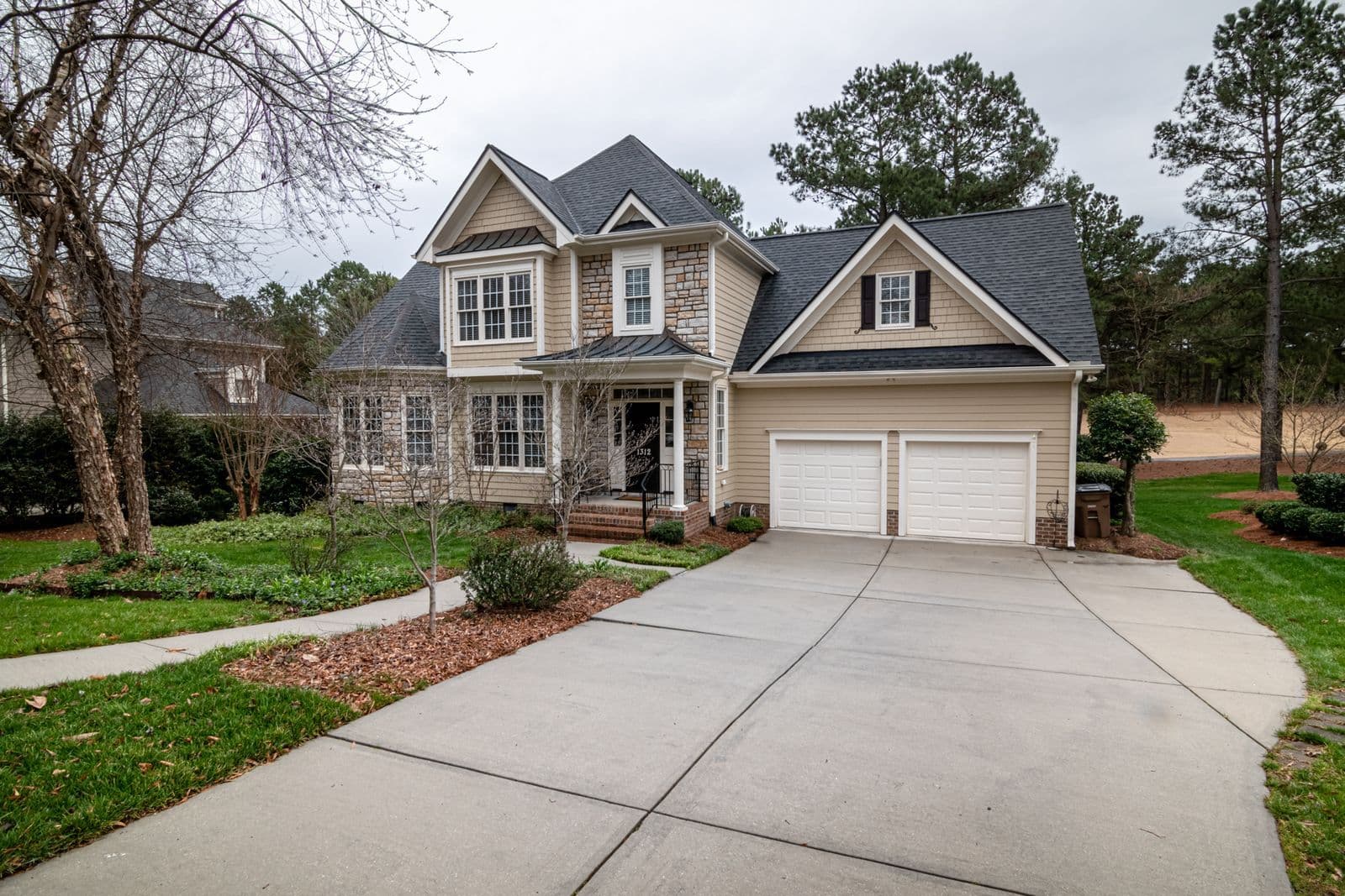 A newer stone and siding home with a wide light-colored driveway, typical of the neighborhoods here