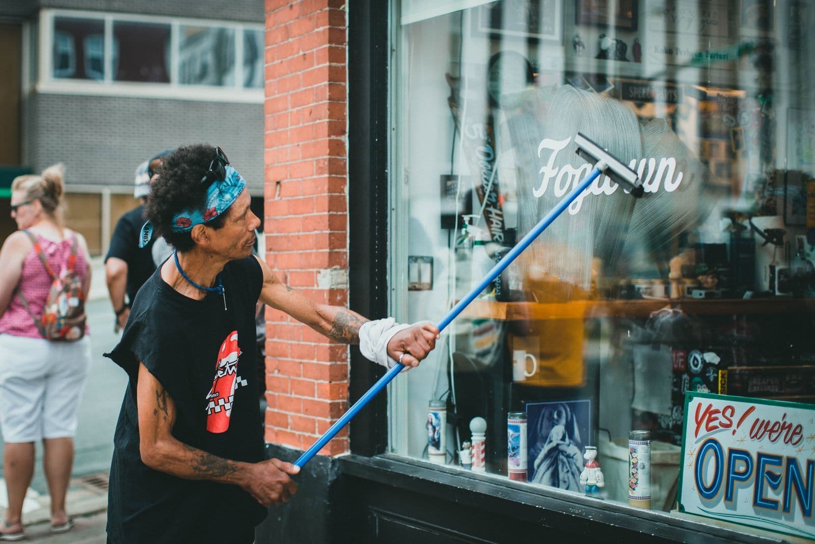 Storefront glass being cleaned on a commercial street, the everyday work on this side of town