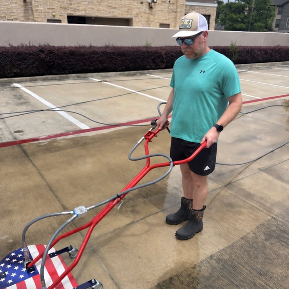 Brandon Wakeland running a surface cleaner on a commercial property