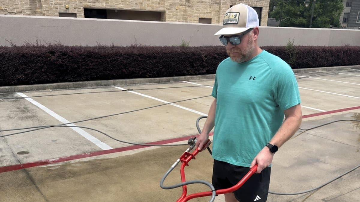 Brandon Wakeland running a surface cleaner on a commercial property
