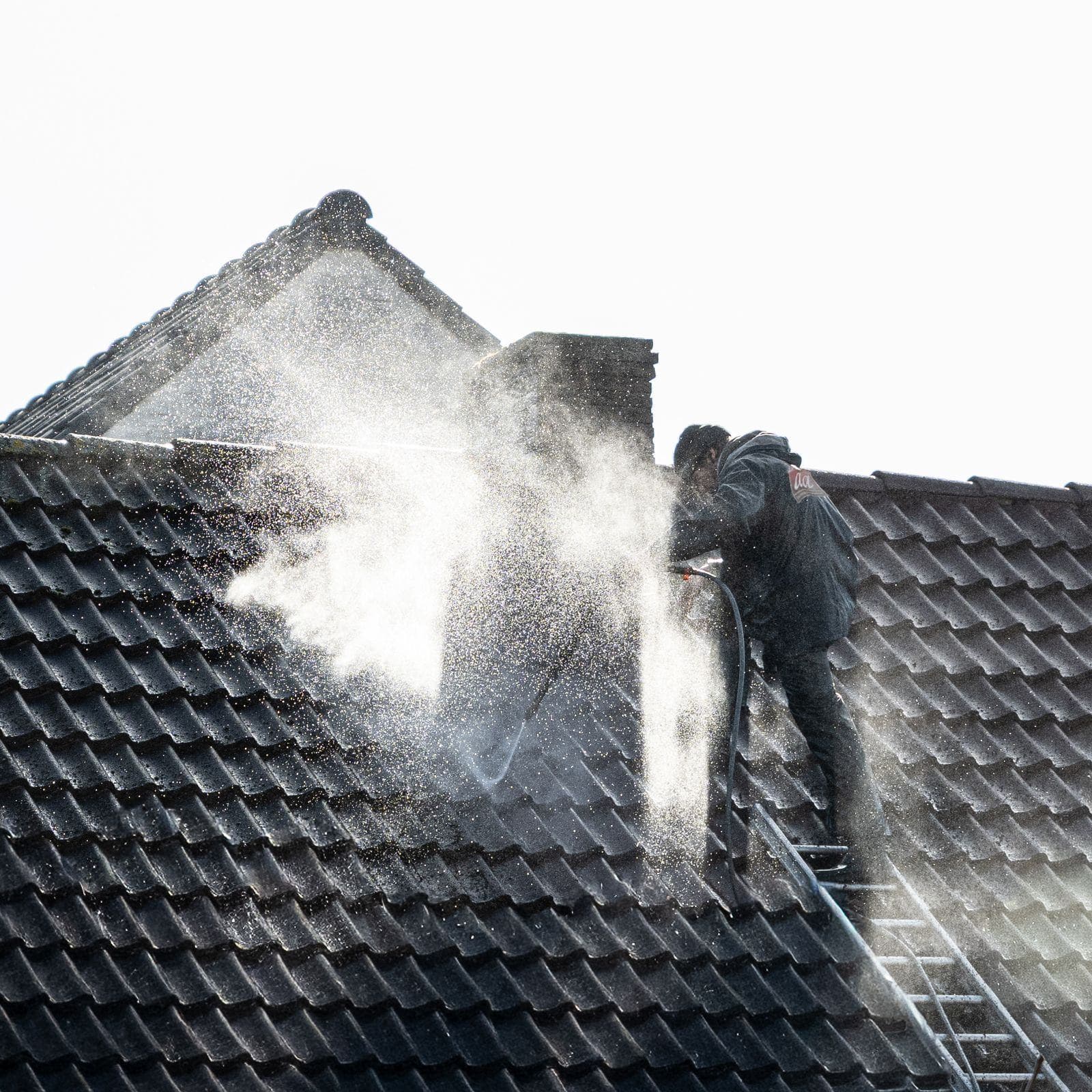 A roof being soft washed at low pressure, the only safe way to treat shingles