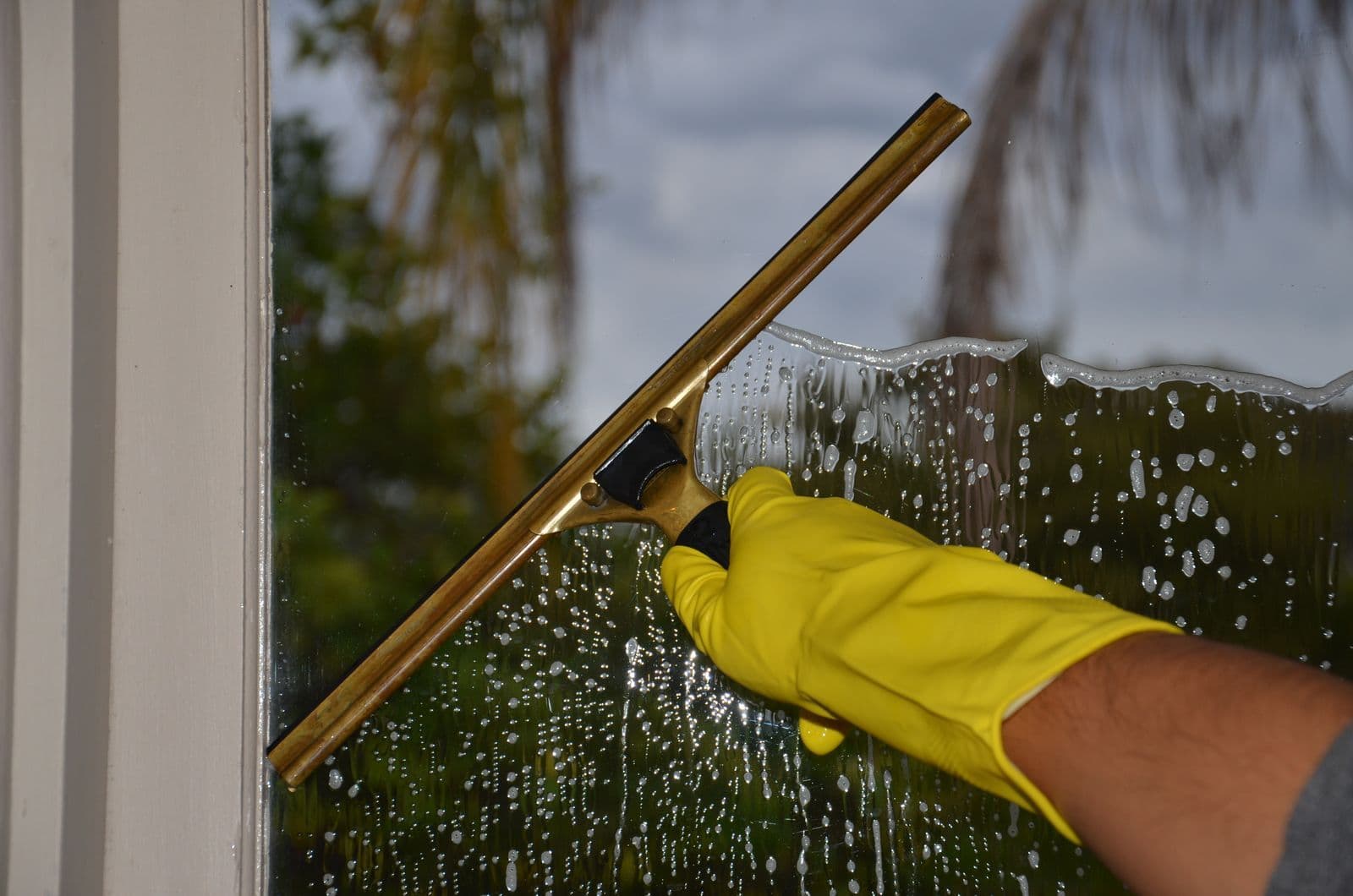 A squeegee pulling water down a pane of glass, leaving it without streaks